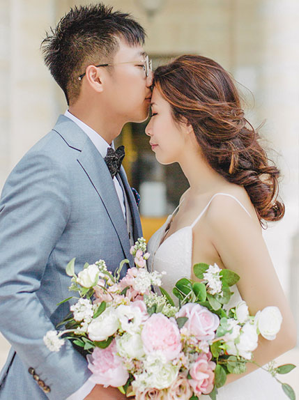 groom in blue suit kisses bride on forehead