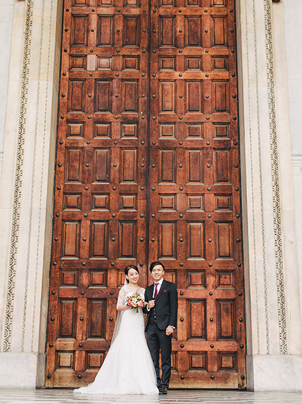 bride and groom pose in front of st pauls cathedral wooden doors